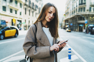 Fototapeta premium Marketing specialist reading work emails on the smartphone while going to the office. Caucasian female texting messages on the mobile phone while crossing the street on a sunny day.