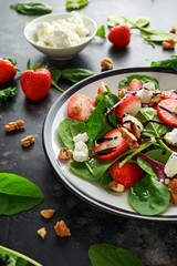 Summer Fruit Strawberry, spinach Salad with walnut, feta cheese balsamic vinegar, kale. in a plate. concepts health food