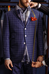 Mature professional Tailor taking measurements for sewing suit at tailors shop. Man with measuring...