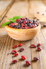 Red raw beans with greens on a wooden table.