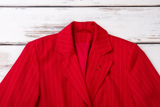 Red classic blazer for women. Female formal apparel on white wooden background. Elegant clothes for women.