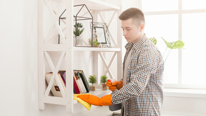 Young man cleaning home with detergents