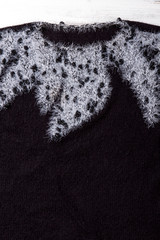 Close up female black winter sweater. Detail of women black woolen sweater with white pattern. Feminine classy outfit.