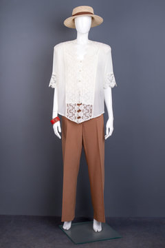 Full length mannequin in elegant attire. Female straw hat and white lace blouse on mannequin. Ladies elegant clothes and accessories.