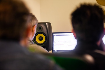 Three people editing a song in a production studio