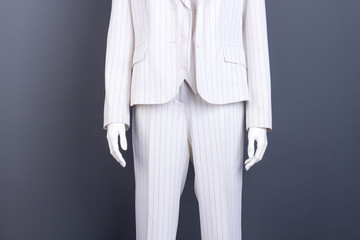 Dummy in white striped suit, cropped image. White blazer and trousers on female mannequin, grey background.