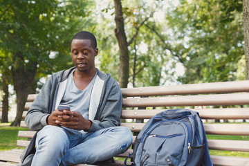Obraz premium Handsome man sitting and using smartphone outdoors