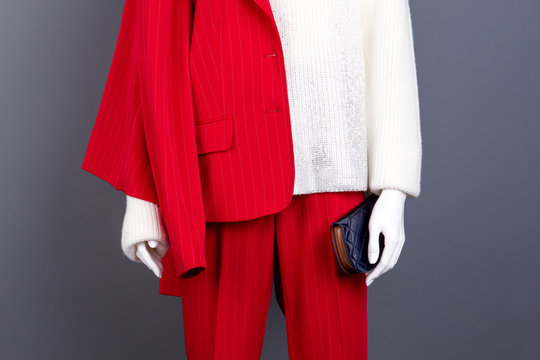 Female mannequin with wallet, cropped image. Red elegant suit and white knitted sweater on female mannequin close up. Ladies fashion clothes and accessories.