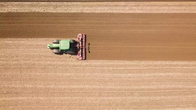 Trattore verde sta arando il terreno per la semina del grano. Vista aerea