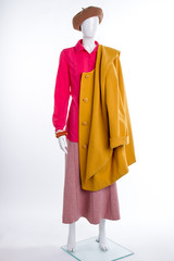 Female mannequin with yellow coat. Beret, blouse, skirt and overcoat. Women fashion look.