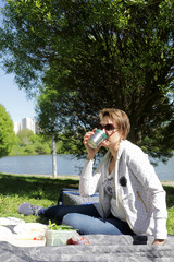 Fototapeta premium Woman has tea on picnic