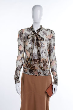 Modern chiffon blouse with bow. Female mannequin dressed in elegant blouse. Female skirt and wallet.