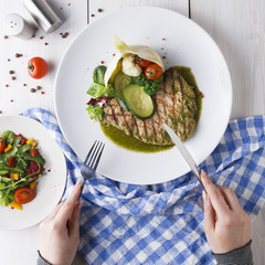 Female eating grilled beefsteak and healthy vegetable salad