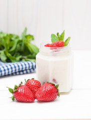 Cream with a strawberry on white wooden background. 
