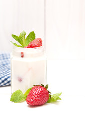 Cream with a strawberry on white wooden background. 
