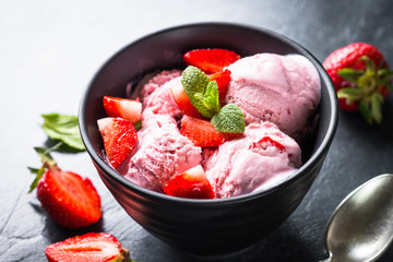 Strawberry ice cream with fresh berries on black.