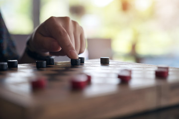 Closeup image of people playing and moving checkers in a chessboard