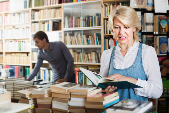 Mature woman looking at open book in book shop