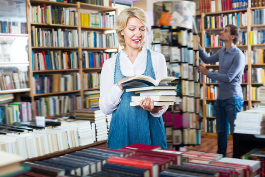 Mature woman reading book in book shop