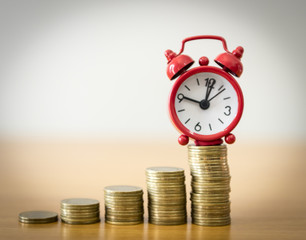 Alarm clock on coin money stacks on a white background.Business concept.