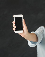 Hand with blank smartphone at black background