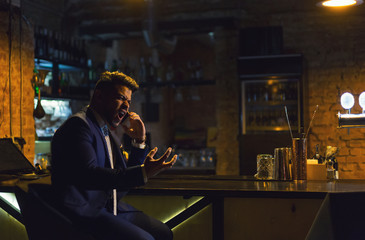 Angry businessman calling on the phone from the bar