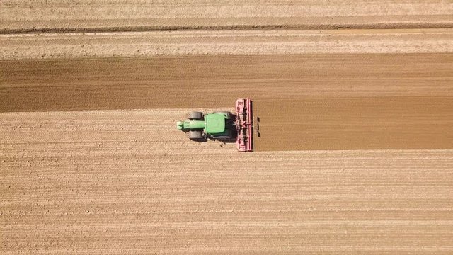 Trattore verde sta arando il terreno per la semina del grano. Vista aerea