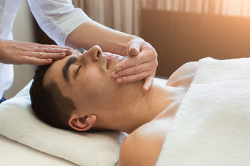 Fototapeta na wymiar Man getting professional facial massage at spa salon