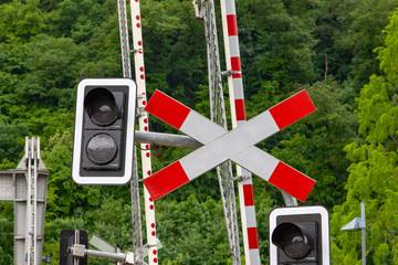 Red Railroad crossing sign in front of a red and white gate and a light