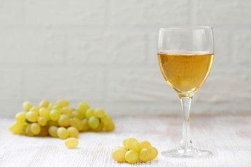 Glass of wine and grapes in the basket on a wooden table.