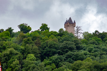 Fototapeta na wymiar Little castle on the top of a little hill behind a broadleaf forest