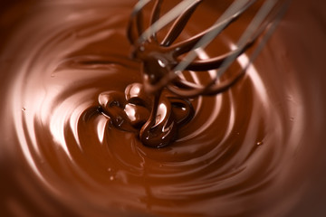 Chocolate. Mixing melted dark chocolate with a whisk. Closeup of liquid hot chocolate swirl. Confectionery