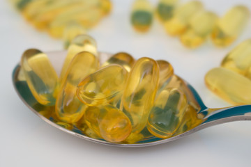 Cod liver oil omega 3 capsuleson the spoon on the white background close up