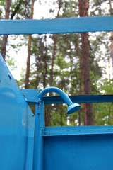 Fototapeta na wymiar Old shower with peeling blue paint in the forest outdoors vertical