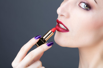 Fototapeta premium Portrait d'une jeune femme appliquant du rouge à levre