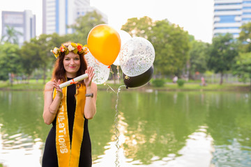Young beautiful woman celebrating graduation at the park in Bang