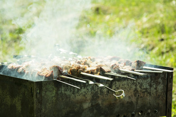 barbecue on the grill in the summer outdoors, hands turn the skewer for even roasting