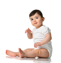 9 month infant child baby  girl toddler sitting in white shirt pointing finger isolated on a white