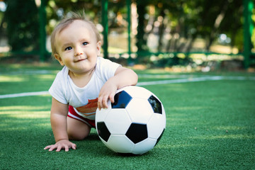 Dreaming little boy at the stadium with a soccer ball. Future football star