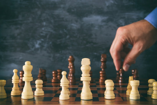 Image of businessman hand moving chess figure over chess board. Business, competition, strategy, leadership and success concept.