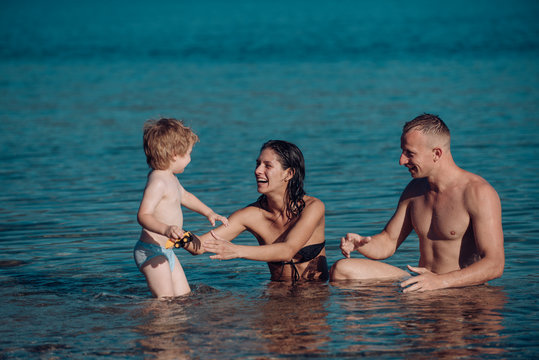 father and mother with son swim in sea on beach. father and mother with happy kid in sea or ocean water.