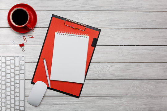 white board desk folder red notebook cup of coffee clock keyboard mouse working process