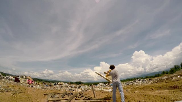 Man throwing misc trash away in a landfill junkyard dump