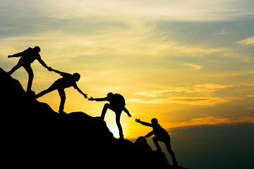 Group of people on peak mountain climbing helping team work with sunset background , travel...