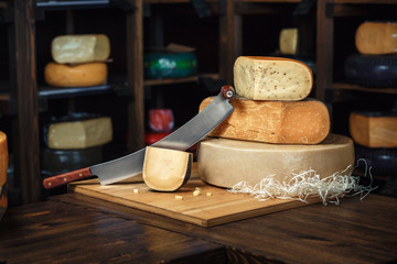 Cheese heads with slices and knives on a wooden board with an interior