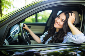 Beautiful woman driver smiling to you from her car on the street