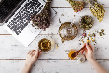 Bunch of medicinal herbs, cup of healthy tea and bag of dry healthy coneflowers on wooden board. Herbal medicine.