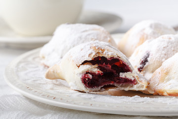 Delicious rustic pastries filled with berry on a ceramic plate on a wooden background.