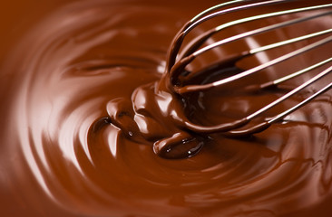 Chocolate. Mixing melted dark chocolate with a whisk. Closeup of liquid hot chocolate swirl. Confectionery