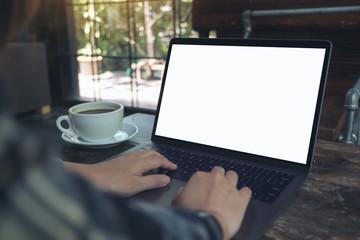Fototapeta premium Mockup image of a businesswoman using laptop with blank white desktop screen with coffee cup on wooden table in cafe